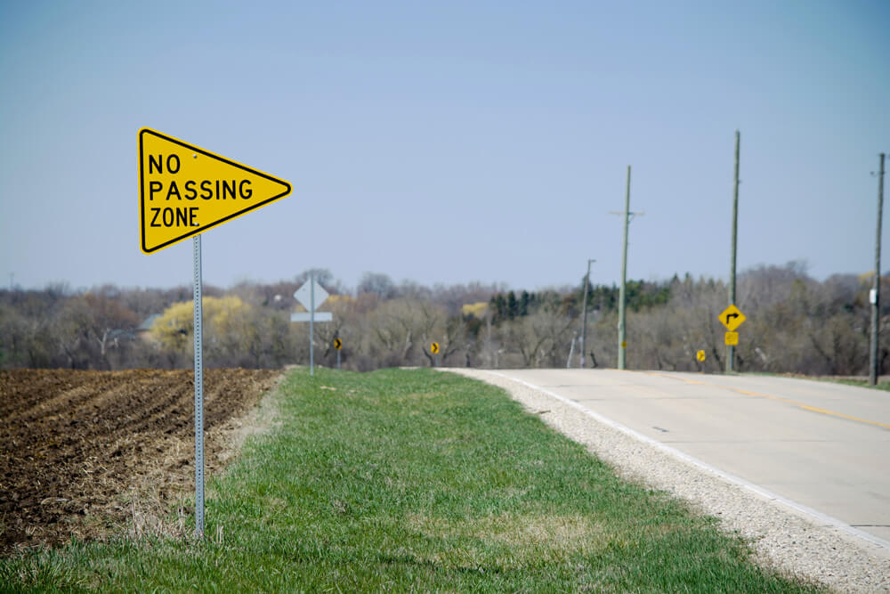 no passing zone sign on a road